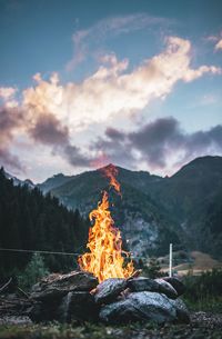 Bonfire on mountain range against sky
