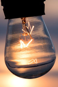 Close-up of illuminated light bulb against sky