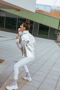 Woman licking mirror on footpath