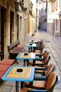 Empty chairs and tables in cafe amidst buildings in city
