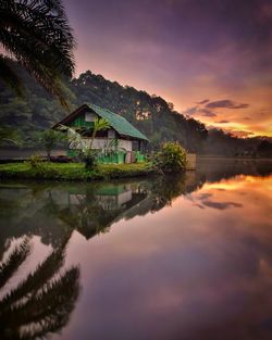 Scenic view of lake by building against sky at sunset