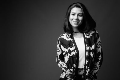 Portrait of smiling young woman against black background