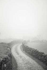 Empty road along landscape against sky