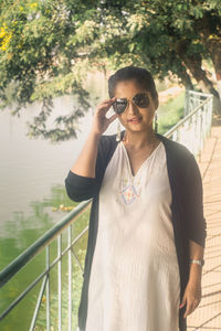 Portrait of young woman standing by railing