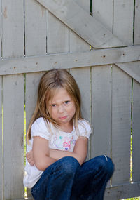 Defiant little girl pouting by a fence