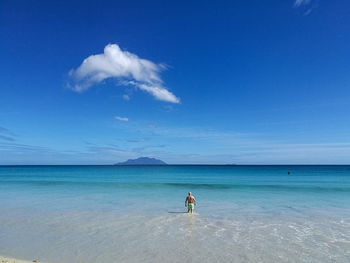 Rear view of man on beach against blue sky