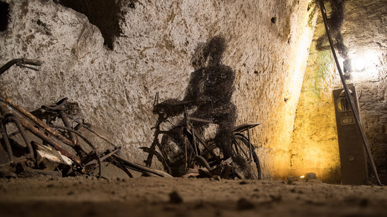 SHADOW OF PEOPLE ON WALL BY ROAD