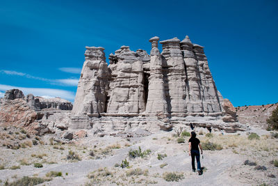 Low angle view of woman standing on rock against blue sky