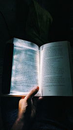 Midsection of person reading book against black background