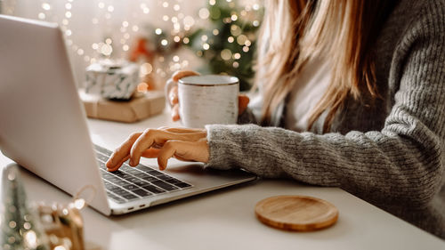 Woman hands with gifts, coffee man g and laptop. online shopping at christmas holidays. freelance