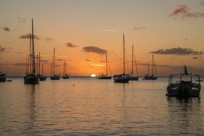 Sailboats in sea at sunset