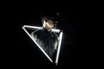 Man standing amidst illuminated lights black background