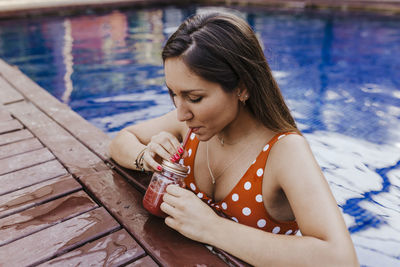 Young woman looking away while sitting on water