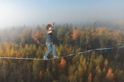 Full length of young man standing against chainlink fence