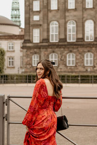 Smiling young woman standing against building