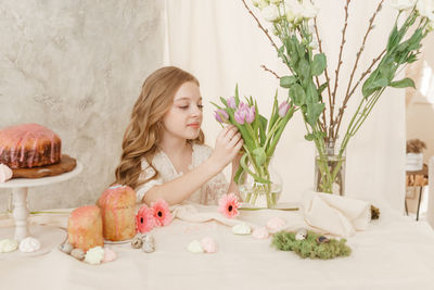 Cute girl smelling flower at home