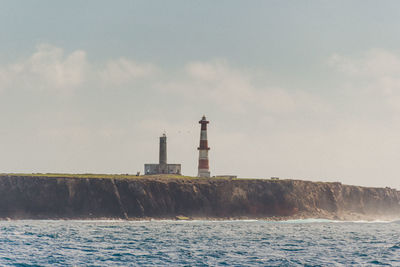 Lighthouse by sea against sky