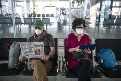 Middle aged couple wear face masks due to the coronavirus pandemic while waiting at a deserted airport in khajuraho, madhya pradesh, india.