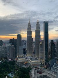 Modern buildings in city against sky during sunset