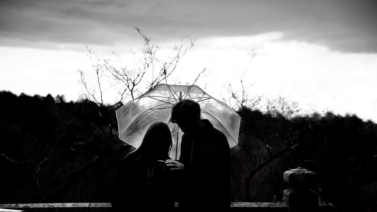 REAR VIEW OF PEOPLE WITH ARMS OUTSTRETCHED AGAINST SKY