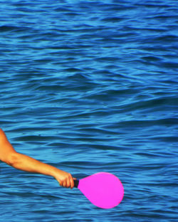 Cropped image of person holding table tennis racket against sea