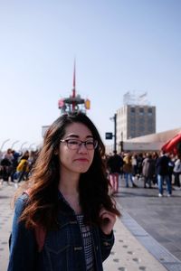 Portrait of beautiful young woman in city against sky