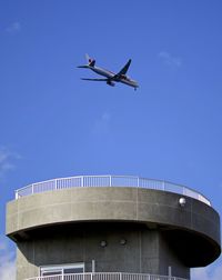 Low angle view of airplane flying against clear blue sky