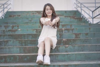 Portrait of a young woman sitting on staircase