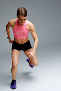 Full length of woman exercising against gray background