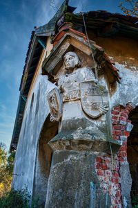 Low angle view of statue by building against sky