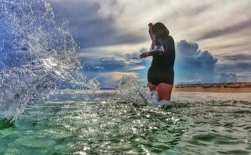 Woman standing by sea against sky