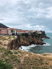 Buildings by sea against sky