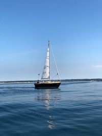 Sailboat sailing on sea against clear sky