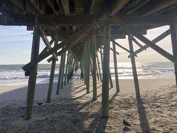 Silhouette of pier on beach against sky