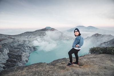 Portrait of woman standing against hot spring amidst mountains
