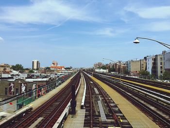 Railroad tracks in city against sky