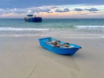 Boat moored on beach against sky