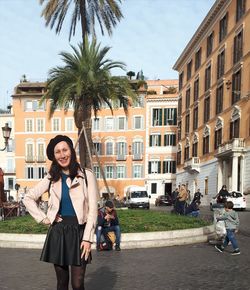 Portrait of young woman with palm trees in city