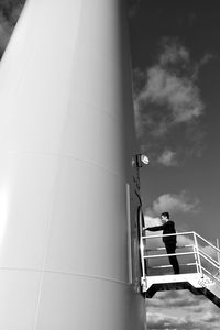 Low angle view of boy standing at entrance of windmill against sky