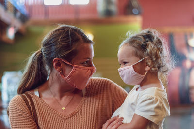 Close-up of mother and daughter wearing mask sanding outdoors