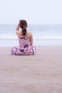 Rear view of woman sitting on beach