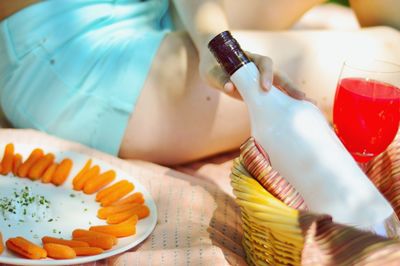 Cropped image of woman hand holding wine bottle at picnic