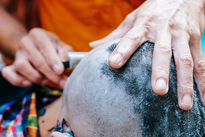 Close-up of man shaving head of boy