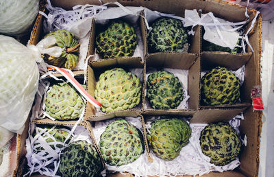 Directly above shot of custard apples in cardboard box at market