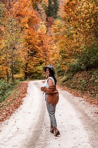 Rear view of woman on path in forest, fall colors, autumn, style, influencer.