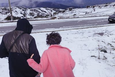 Rear view of people on snow covered mountain