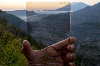 Person hand on mountain against sky