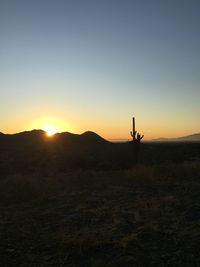 Silhouette person on field against sky during sunrise