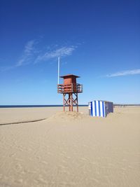 Lifeguard hut on beach against clear blue sky