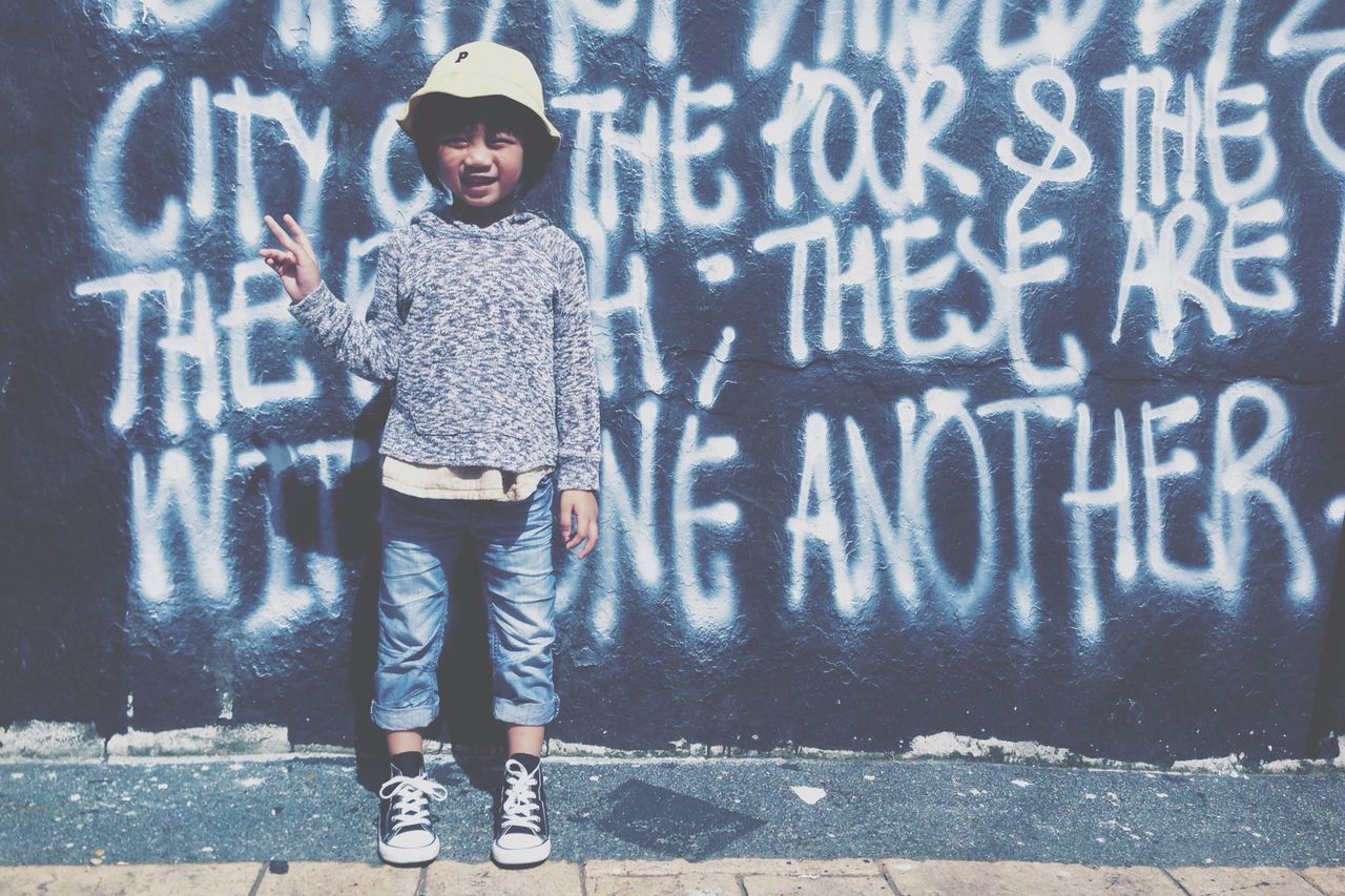 lifestyles, casual clothing, graffiti, standing, full length, front view, person, wall - building feature, leisure activity, young adult, looking at camera, portrait, three quarter length, text, young women, outdoors, western script, street